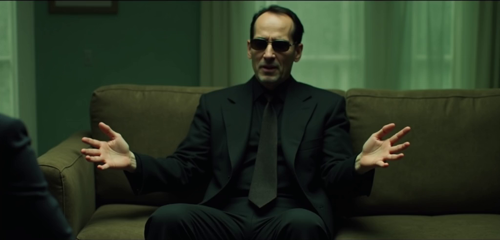 Official reference image of a suited man seated on a sofa